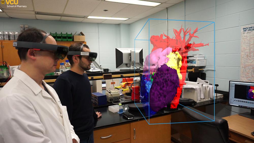 Dan Tang, M.D. (left), the Richard R. Lower Professor in Cardiovascular Surgery in the VCU School of Medicine, stands beside Aldrin Castillo as the two view a 3-D model of Aldrin’s heart in augmented reality. Dr. Tang used the model to help his team plan a 2018 surgery in which they removed a tumor from Aldrin’s heart.