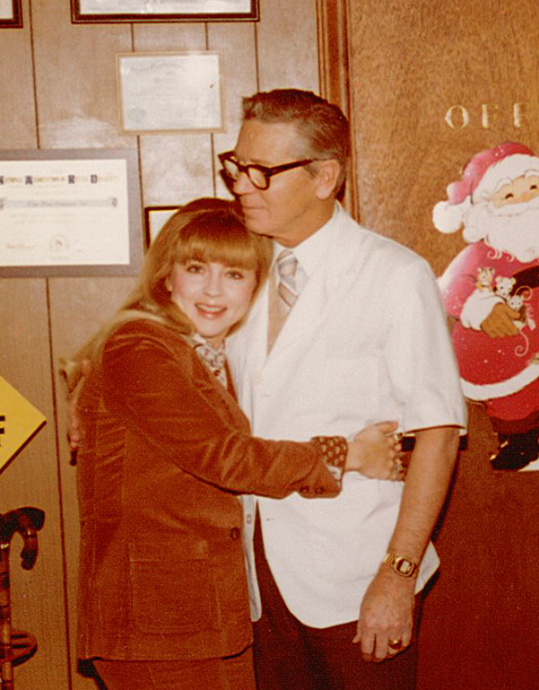 Home for the holidays from grad school, Donna Clevinger hugs her father in his drugstore in Southwest Virginia. Lawrence Earle Clevinger proudly wears his MCV class ring, which is inscribed with his Kappa Psi Fraternity insignia. 