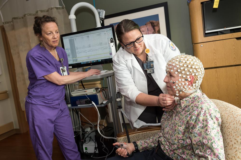 Kathryn Holloway, M.D. (left), observes Rachel Van Aken as she adjusts a 256-electrode cap that Dr. Holloway’s team is using in preclinical studies to identify signatures of various parts of the brain that will serve as guides when surgeons target cognitive challenges, such as dementia, using deep brain stimulation. Photo: Kevin Schindler