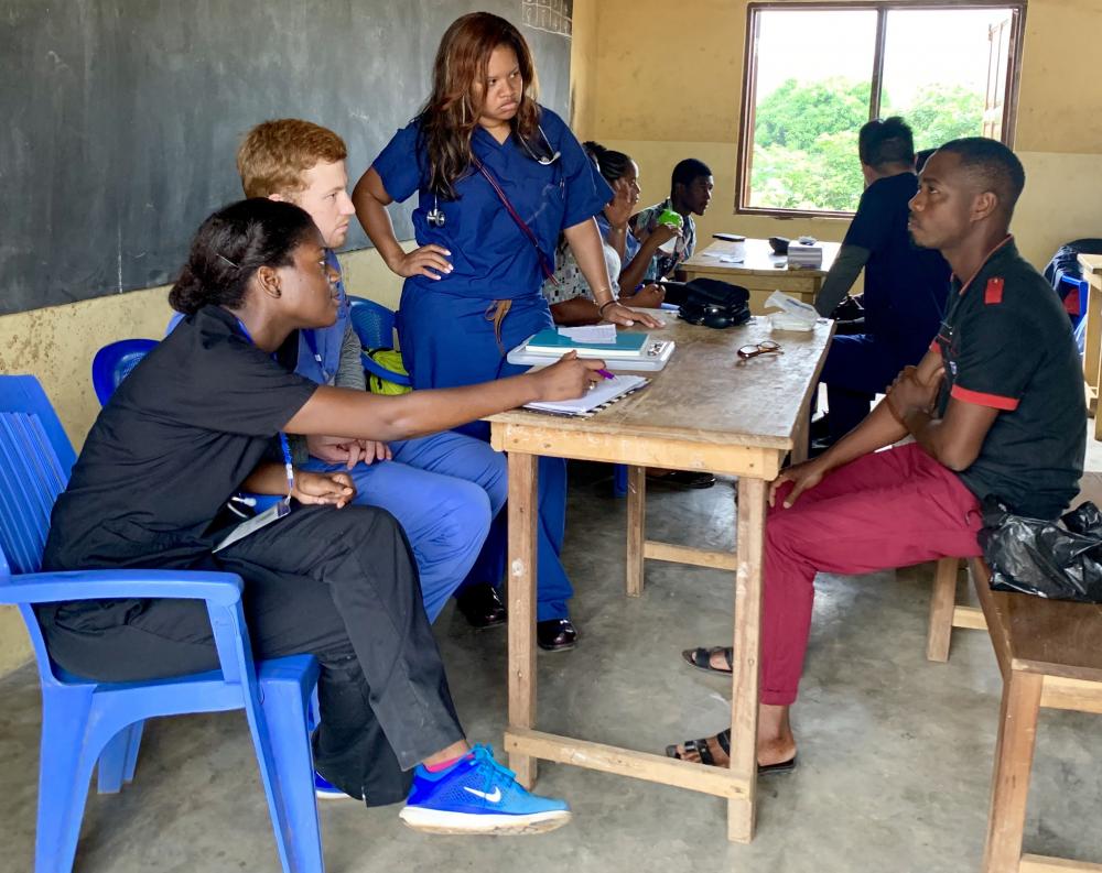 VCU School of Medicine students Nicole Karikari (foreground) and Patrick Murphy (seated next to Nicole) consult a Ghanaian clinic patient alongside a family medicine physician from Bon Secours Health System. Photo courtesy of Nicole Karikari