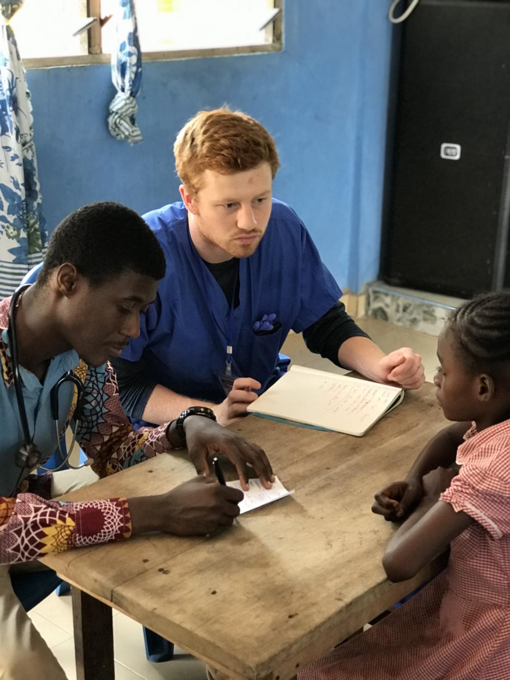 VCU School of Medicine student Patrick Murphy, alongside a recently graduated Ghanaian physician, consult a young girl at a clinic. Photo courtesy of Nicole Karikari