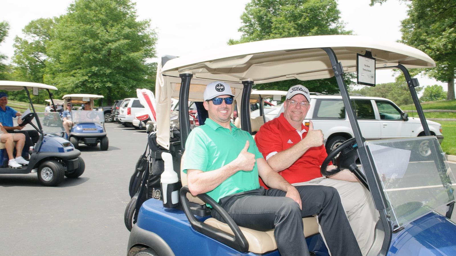 Golfers giving a thumbs-up in a golf cart