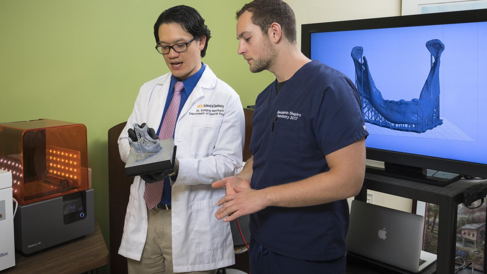 Sompop Bencharit, D.D.S., Ph.D., and a dental student discuss a 3D-printed dental model that was printed in Dr. Bencharit’s lab. Photo by Allen Jones, VCU University Marketing
