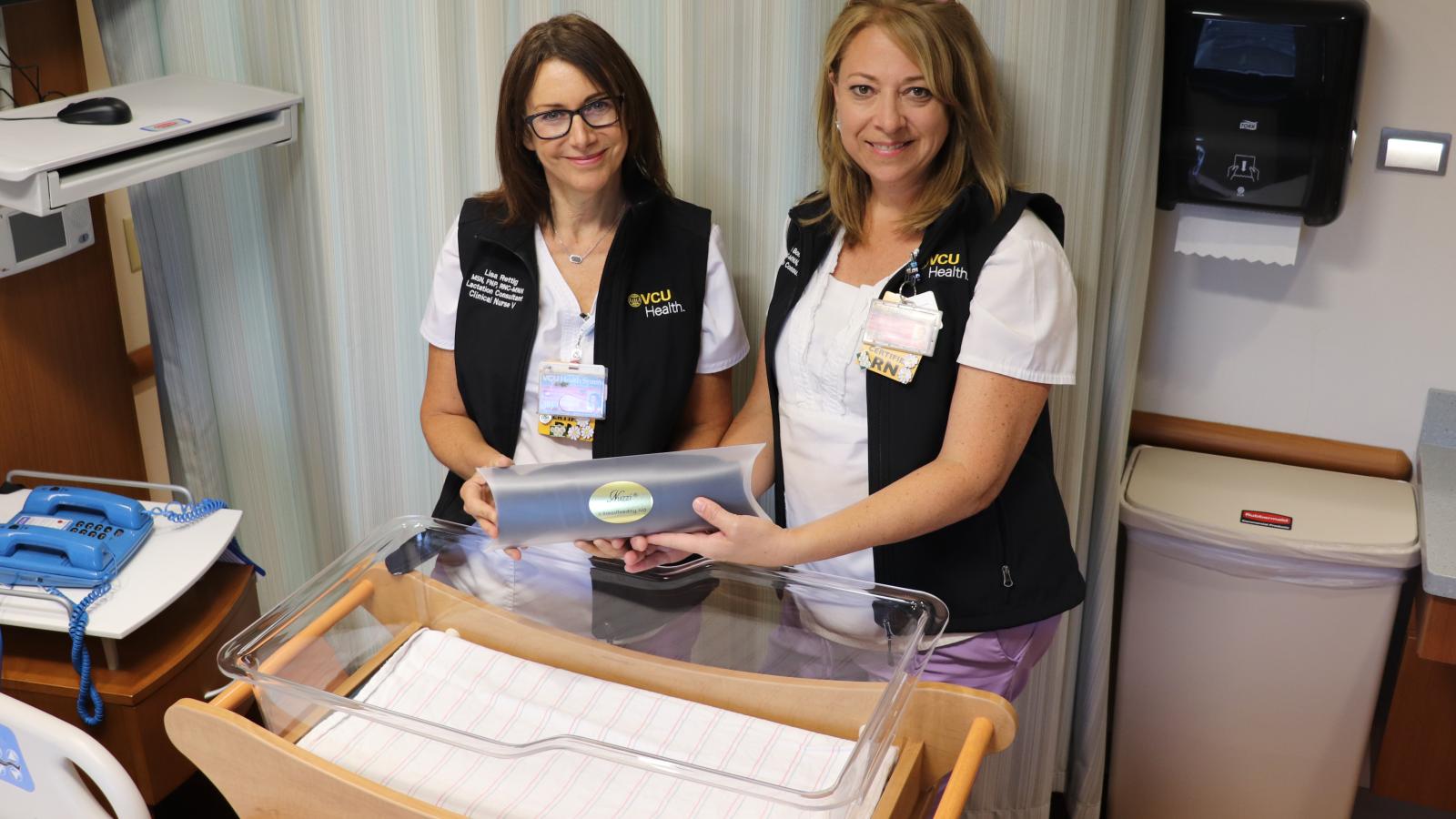 Lisa Rettig (left) and Kristie Bonovitch, both nurses in VCU Health’s Mother-Infant Unit, show a packaged Nuzzi, which the two invented alongside VCU Health colleagues Sharon Brinkley, a nurse in the Labor and Delivery Unit, and Gauri Gulati, M.D., assistant professor of pediatrics. 