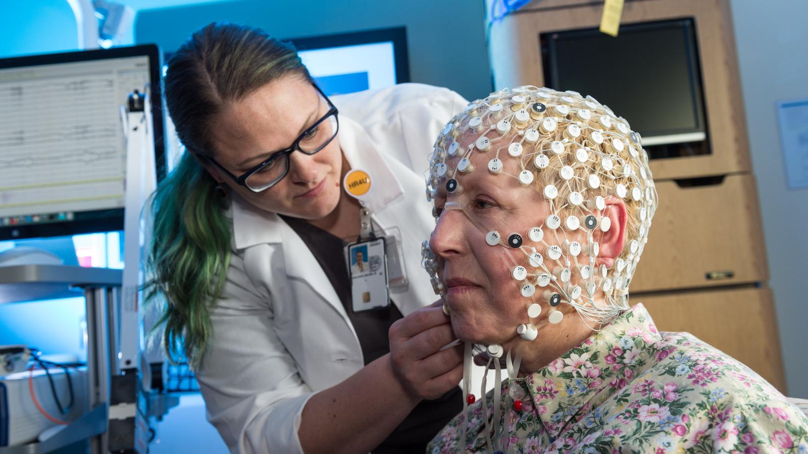 Rachel Van Aken, an intraoperative monitoring technologist on Dr. Kathryn Holloway’s research team, adjusts a cap with 256 electrodes that the team uses in its research. The data it gathers will guide brain surgeons in using deep brain stimulation to treat cognitive challenges such as dementia in patients battling Parkinson’s disease. Photo: Kevin Schindler 